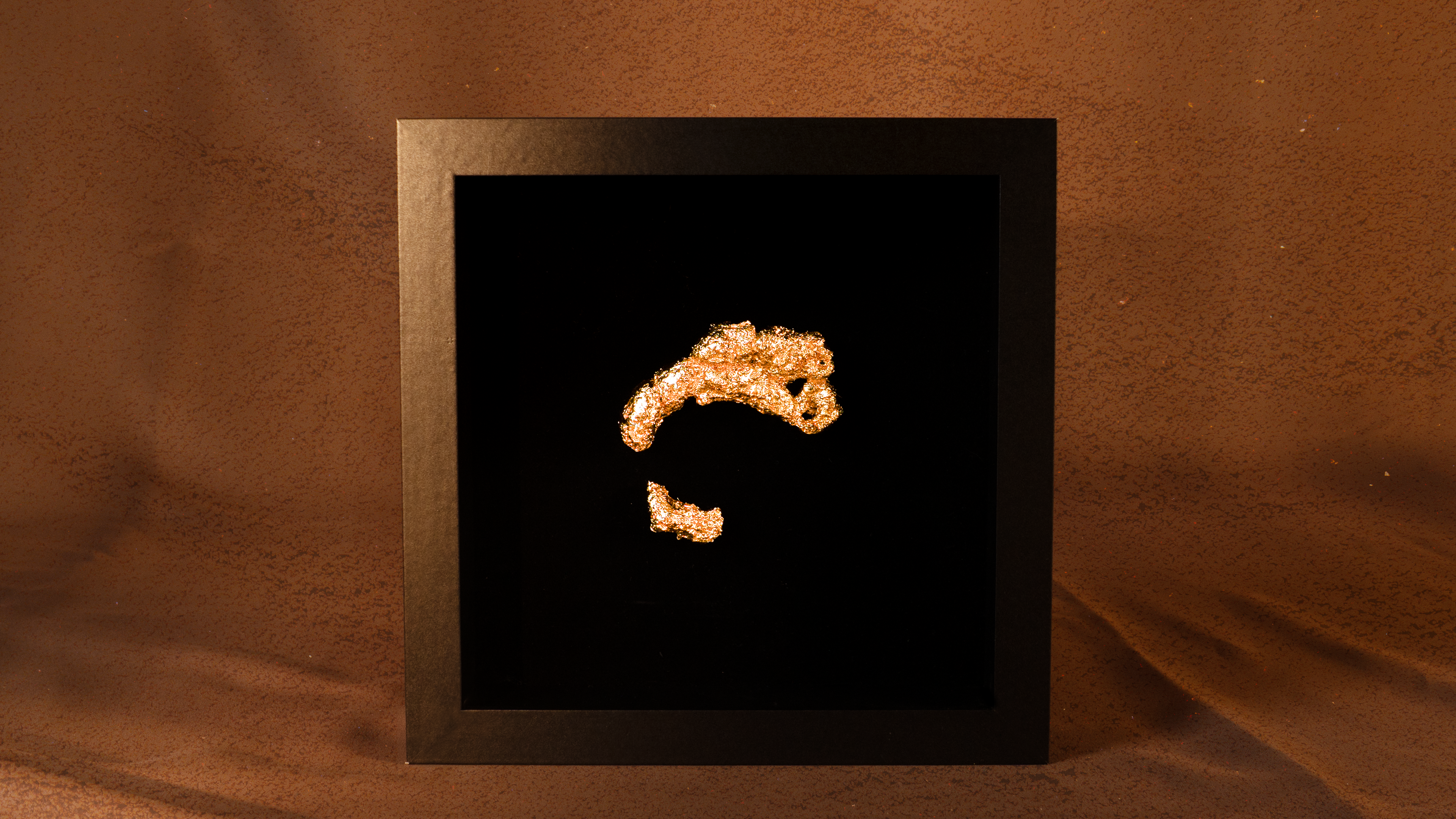 Gold-colored object resembling a stylized letter 'C' on a black background within a gold frame.