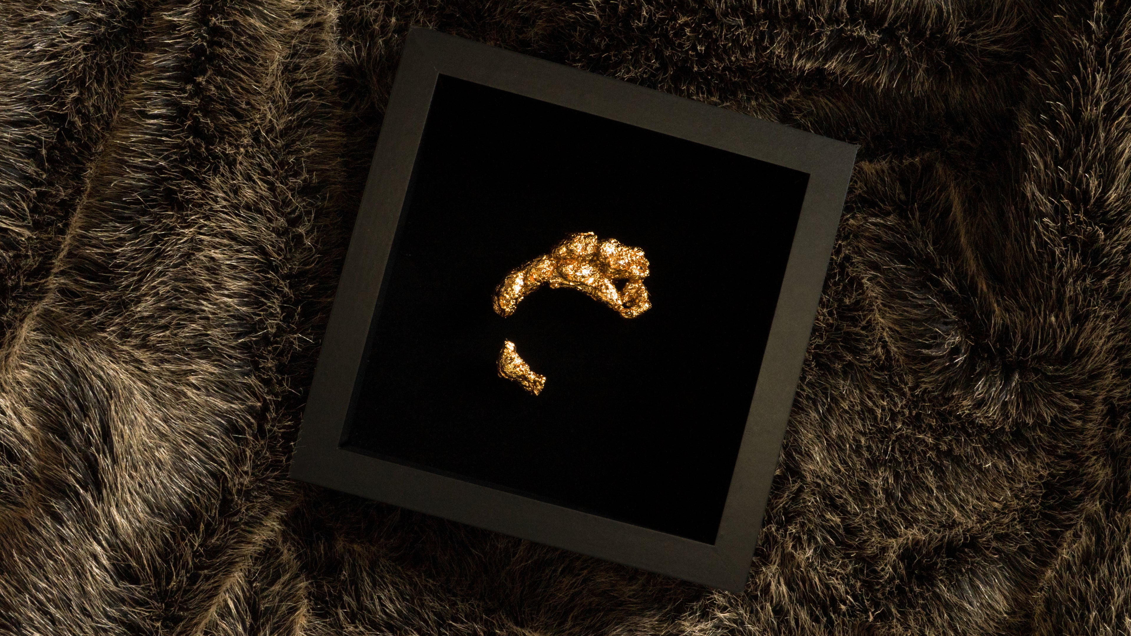 Gold ring on a black square frame on a textured brown surface